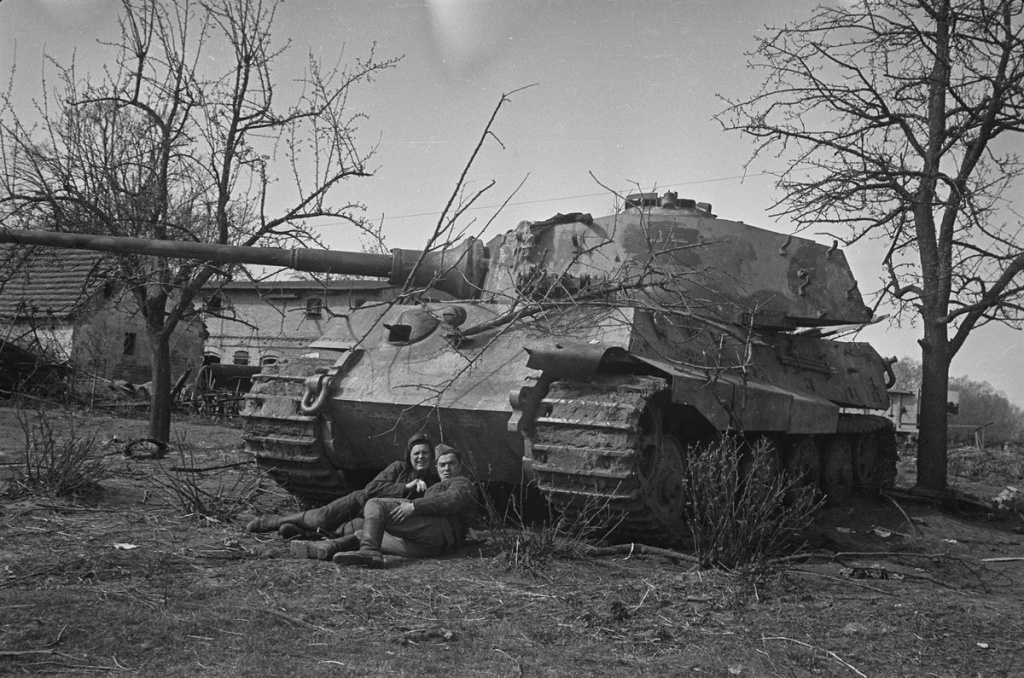 Два советских танкиста позируют перед немецким тяжёлым танком Pz.Kpfw.VI Ausf.B «Королевский тигр» из состава 502-го тяжёлого танкового батальона СС (SS-s.Pz.Abt.502), брошенным в районе Зееловских высот, апрель 1945 г. Источник фото: http://waralbum.ru